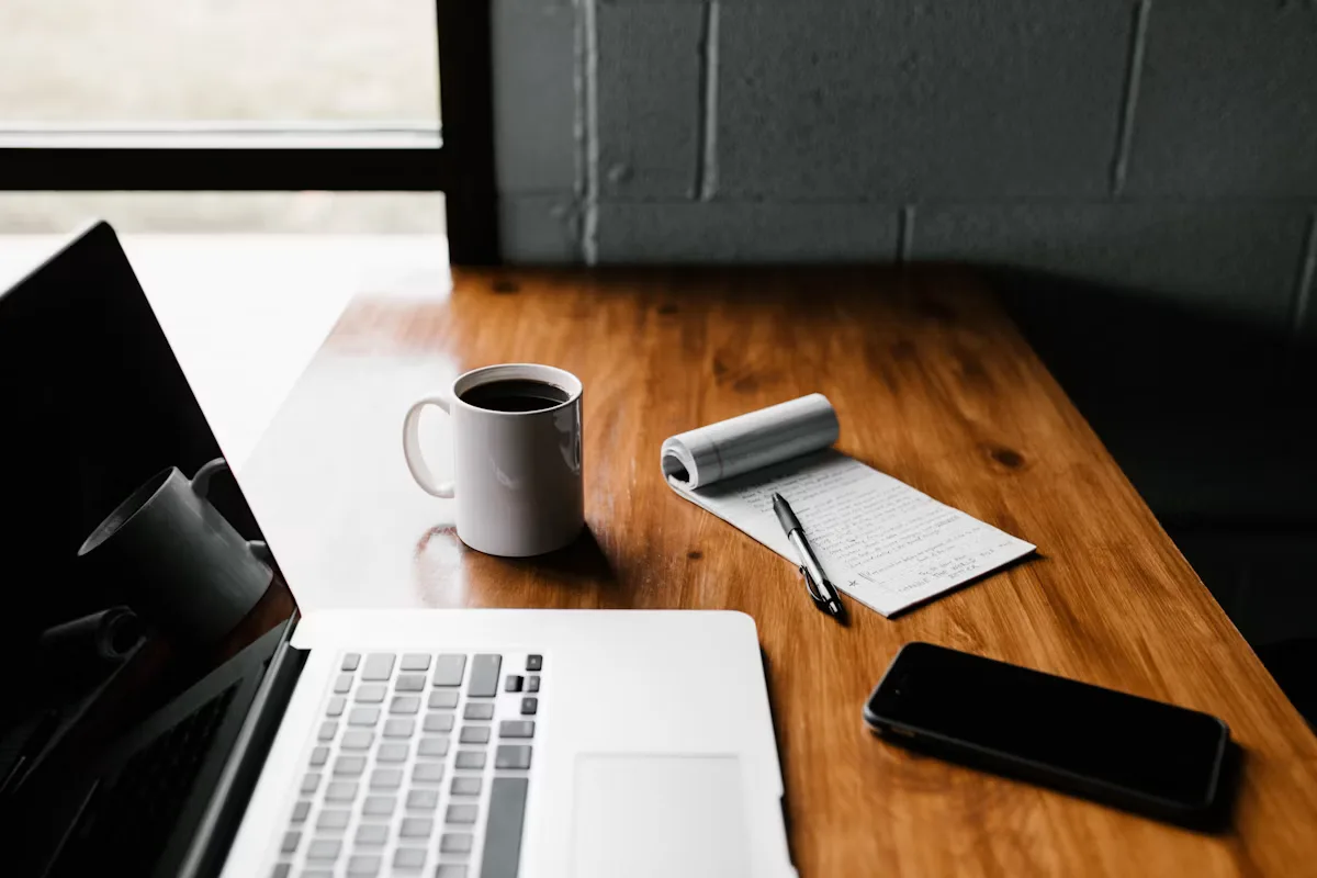 A laptop, mug, and phone arranged on a desk