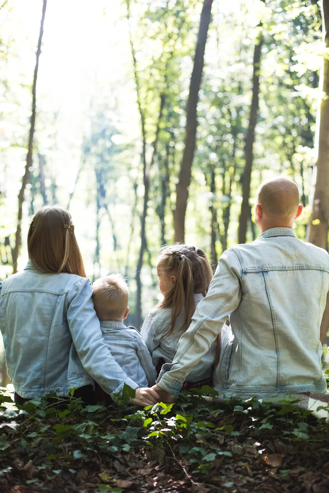 Parents and two children spending time together outdoors near trees
